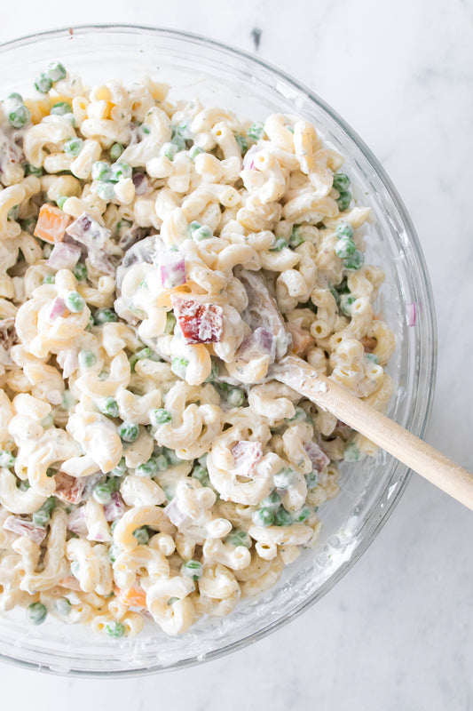 bacon ranch pasta salad in glass bowl served with wooden spoon