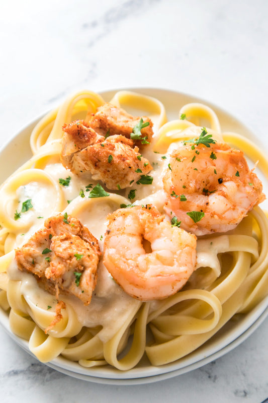 alfredo sauce over fettuccine noodles topped with chicken and shrimp