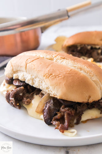 Up close vertical shot of philly cheesesteak with onions, mushrooms and provolone cheese on a hoagie bun