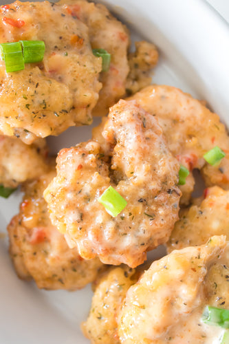 bang bang shrimp topped with green onions on serving platter