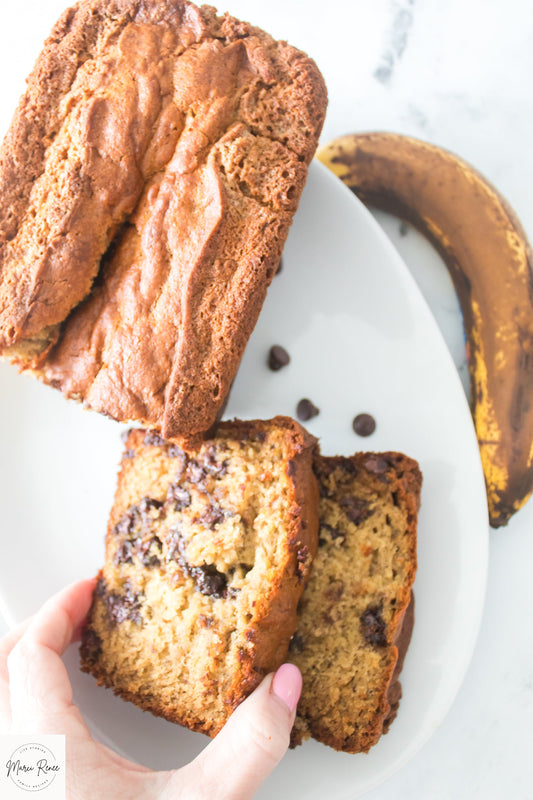 hand grabbing slice of chocolate chip banana bread from platter