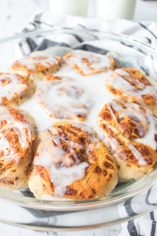 close up vertical shot of cinnamon rolls with icing baked in milk