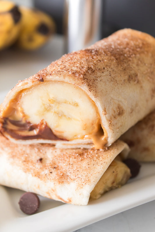 Peanut Butter banana roll up cut in half with creamy peanut butter and a whole banana