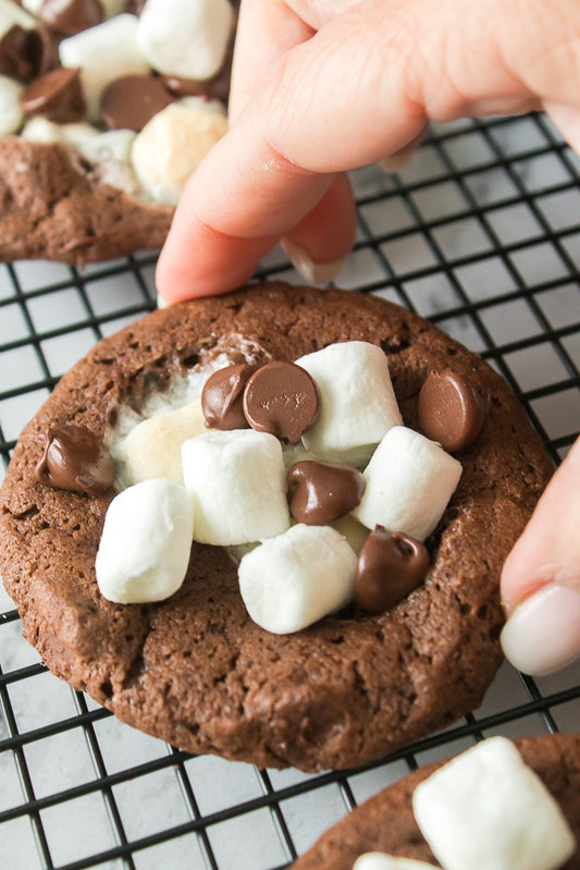 hand picking up a hot chocolate cookie from cooling rack