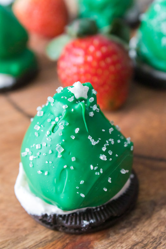 chocolate covered strawberry coated in green candy melts with white sugar sprinkles and star to resemble christmas tree