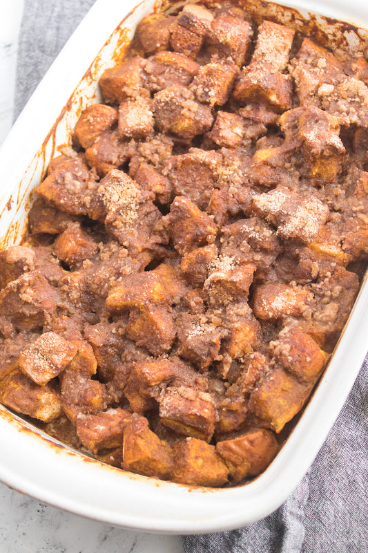 close up vertical shot of pumpkin french toast bake in white casserole dish with streusel topping