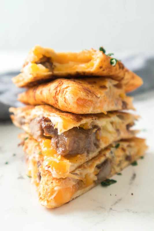 steak quesadilla cut into quarters stacked on top of one another to show melty cheese and pieces of steak