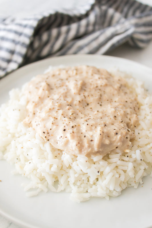 close up vertical image of white rice topped with creamy shredded chicken breasts