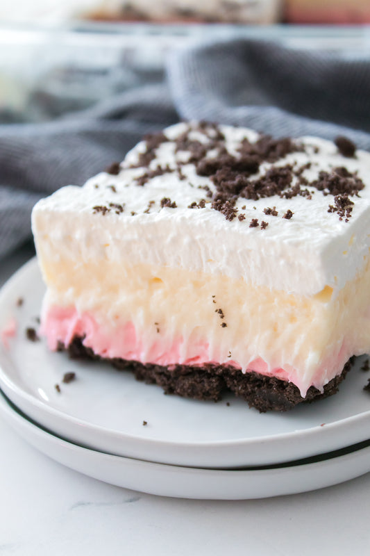 close up shot of no bake oreo dessert with pink cheesecake layer on white plate