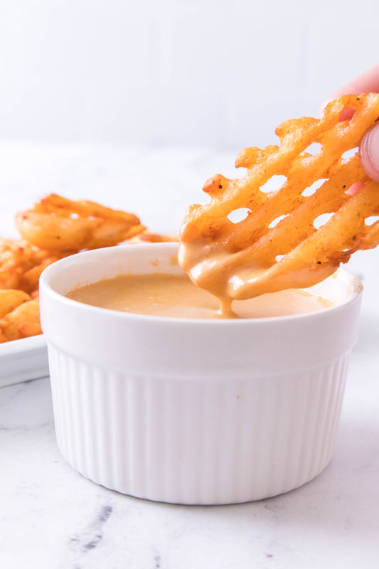 waffle fry being dipped into chick fil a sauce in white ramekin