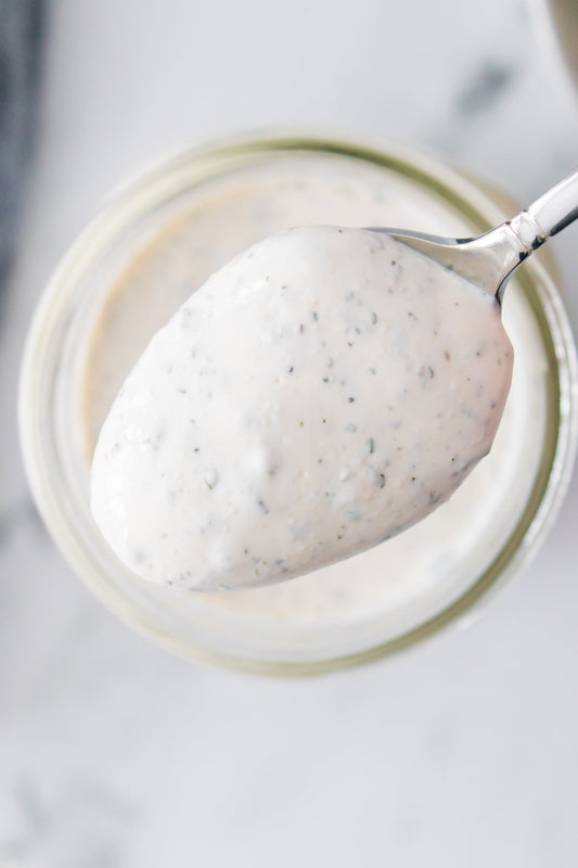 spoon holding ranch dressing over mason jar full of ranch dressing