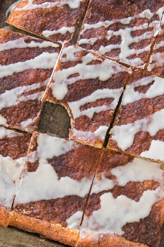 overhead shot of cinnamon sugar dessert pizza on baking sheet with bite taken out of a slice