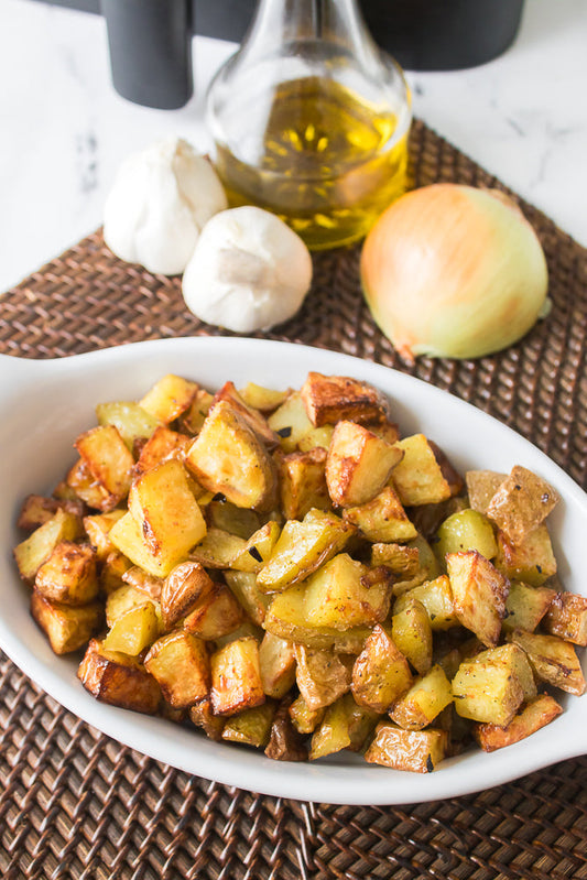 close up vertical shot of roasted potatoes in white serving dish