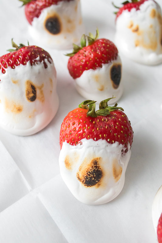 strawberries dipped in marshmallow fluff on white parchment paper