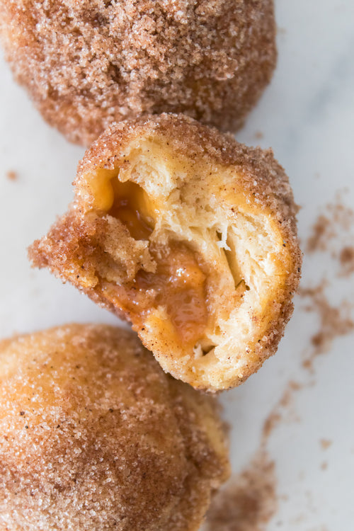 overhead shot of caramel bomb with bite taken out dipped in cinnamon sugar mixture